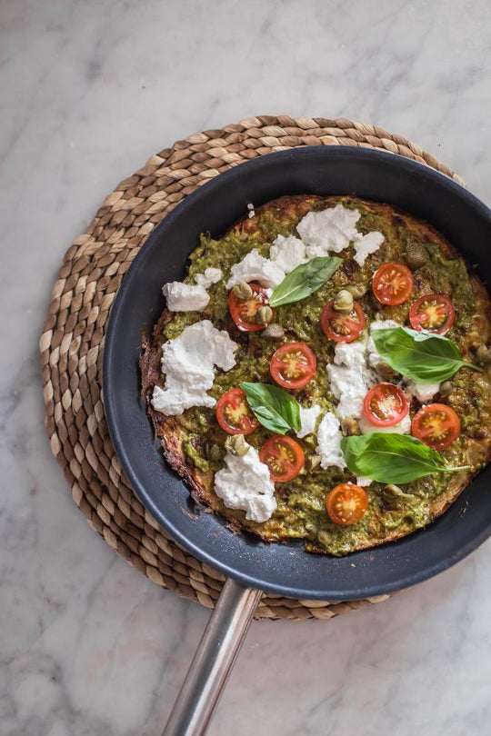 Pizza de base de calabacín con pesto, tomates y ricotta